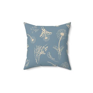 A square throw pillow with a light blue background and white floral patterns.