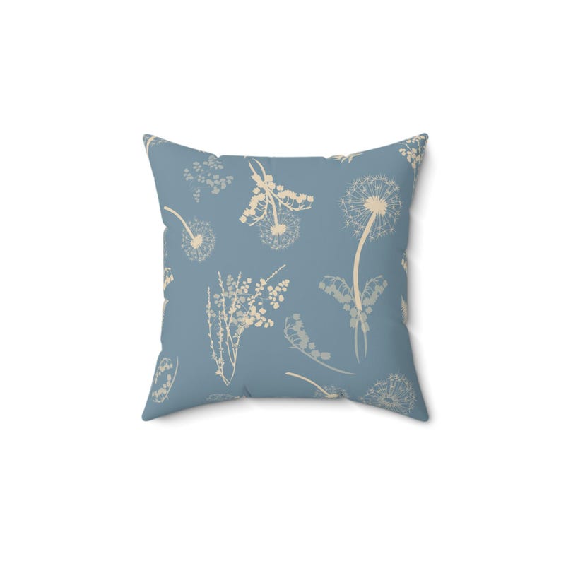 A square throw pillow with a light blue background and white floral patterns.