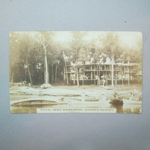 May include: A black and white vintage postcard showing a large wooden building with a porch and people standing on it. The building is surrounded by trees and there is a lake in the foreground with people in boats. The text on the postcard reads "Royal-Wah-Wash-Kesh, Summer Resort."
