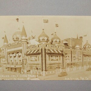 Könnte beinhalten: Eine alte Schwarzweiß-Postkarte, die das Worlds Only Corn Palace in Mitchell, South Dakota, zeigt. Das Gebäude ist aus Mais gebaut und hat ein fantasievolles, schlossartiges Design mit mehreren Türmen und Flaggen.