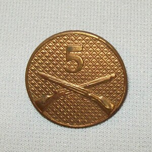 May include: A gold-colored metal button with a crossed rifles design and the number "5" in the center.