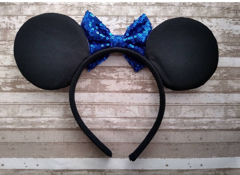 May include: Black headband with large black fabric ears and a blue sequin bow.