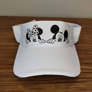 May include: White visor with a black and white image of Mickey Mouse and Minnie Mouse peeking over the top.