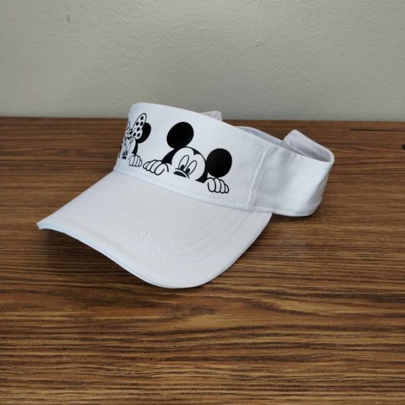 May include: White visor with a black and white print of Mickey Mouse and Minnie Mouse peeking over the brim.