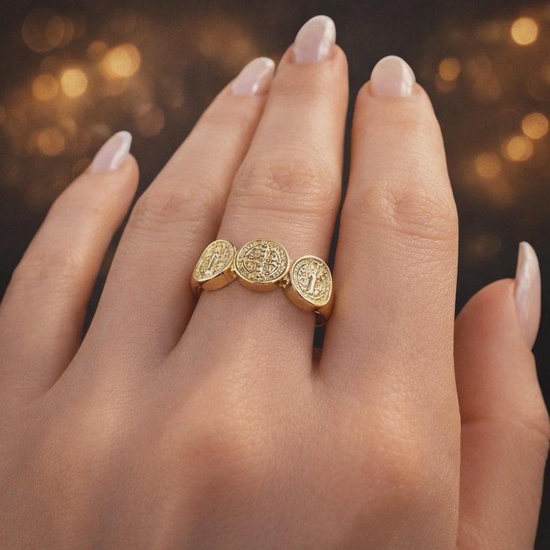 Puede incluir: Un anillo dorado con tres medallones circulares detallados. El dise&ntilde;o del anillo es probablemente religioso o simb&oacute;lico. El anillo se lleva en un dedo, destacando la intrincada artesan&iacute;a y el dise&ntilde;o. Una pieza de declaraci&oacute;n.