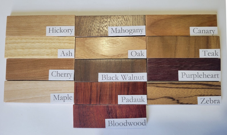 May include: A close-up of 12 wood samples, each labeled with its wood type. The wood types are Hickory, Mahogany, Canary, Ash, Oak, Teak, Cherry, Black Walnut, Purpleheart, Maple, Padauk, Zebra, and Bloodwood.