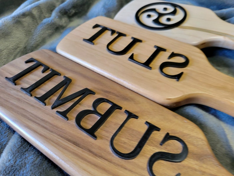 Pu&ograve; includere: Tre palette di legno con lettere nere. La paletta superiore ha un simbolo di tre cerchi intrecciati. La paletta centrale dice "21 SLU". La paletta inferiore dice "21 SUBM1T".