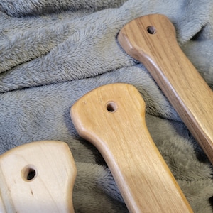 Pu&ograve; includere: Tre maniglie in legno con diverse venature e finiture. Le maniglie hanno un foro al centro e probabilmente sono per una porta o un cassetto.