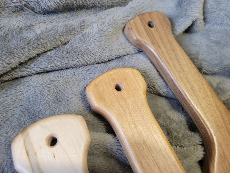 Pu&ograve; includere: Tre maniglie in legno con diverse venature e finiture. Le maniglie hanno un foro al centro e probabilmente sono per una porta o un cassetto.
