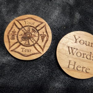 May include: Two round wooden coasters. One features a firefighter emblem with the words "Your Text" and the other says "Your Words Here". The coasters are light brown and appear to be laser engraved.