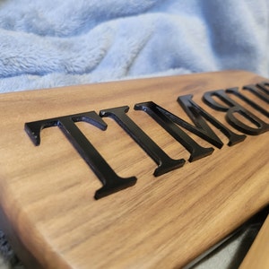 Pu&ograve; includere: Una paletta di legno con il nome "TIMMY" inciso in lettere nere.