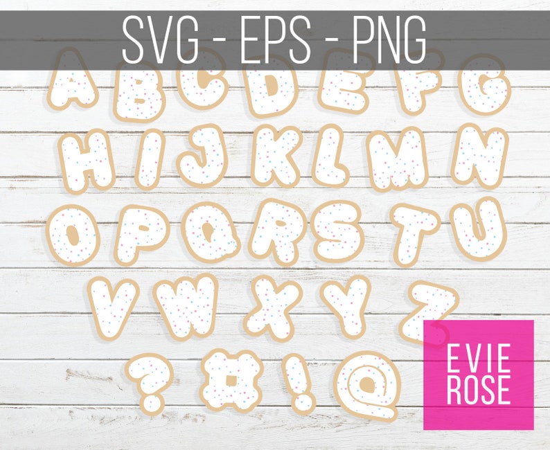 May include: A set of cookie-shaped alphabet letters and symbols with white frosting and colorful sprinkles. The letters are A through Z, and the symbols are a question mark, a hashtag, an exclamation point, and an at symbol. The letters and symbols are on a white wood background.