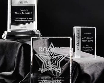 Könnte beinhalten: Drei klare Glas-Award-Plaketten mit graviertem Text. Die obere Plakette lautet "Mitarbeiter des Monats" und wird an "Marc Johnson" verliehen. Die mittlere Plakette lautet "Rookie des Jahres 2022" und wird an "Sam Johnson" verliehen. Die untere Plakette lautet "Star Award" und wird an "Jennifer Manders" verliehen.