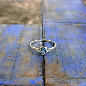 May include: A silver ring with a light blue oval gemstone set in the center.