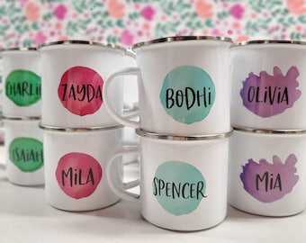 May include: Set of eight white enamel mugs with colorful watercolor designs and names, including Bodhi, Zayda, Olivia, Mila, Spencer, Mia, Isaiah, and Charlie.