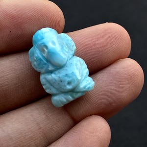 K&ouml;nnte beinhalten: Eine hellblaue, geschnitzte Edelsteinfigur eines Elefanten. Der Elefant ist detailliert mit sichtbaren Sto&szlig;z&auml;hnen, R&uuml;ssel und Ohren. Der Edelstein hat ein leicht gesprenkeltes Aussehen mit Variationen in der blauen Farbe.