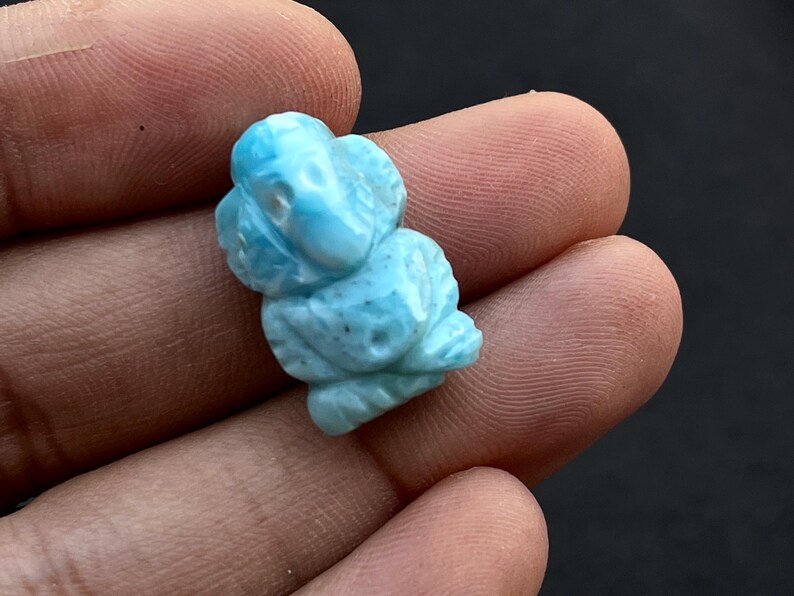 K&ouml;nnte beinhalten: Eine hellblaue, geschnitzte Edelsteinfigur eines Elefanten. Der Elefant ist detailliert mit sichtbaren Sto&szlig;z&auml;hnen, R&uuml;ssel und Ohren. Der Edelstein hat ein leicht gesprenkeltes Aussehen mit Variationen in der blauen Farbe.