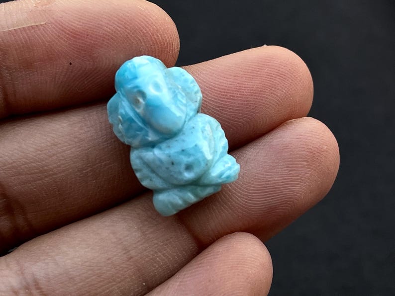 K&ouml;nnte beinhalten: Eine hellblaue, geschnitzte Edelsteinfigur eines Elefanten. Der Elefant ist detailliert mit sichtbaren Sto&szlig;z&auml;hnen, R&uuml;ssel und Ohren. Der Edelstein hat ein leicht gesprenkeltes Aussehen mit Variationen in der blauen Farbe.