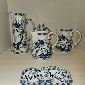 May include: A set of three blue and white porcelain teapots with a floral design. The teapots are labelled "Vienna Woods Fine China".