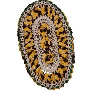 Könnte beinhalten: Eine gehäkelte ovale Tischdecke mit einem braunen, gelben und grünen Muster. Die Tischdecke hat ein zartes Spitzenmuster und ist perfekt, um Ihrem Zuhause einen Hauch von Vintage-Charme zu verleihen.
