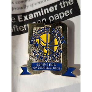 May include: Gold and blue Golden State Warriors pin with the team logo and the text "1946-1996 NBA Charter Member".