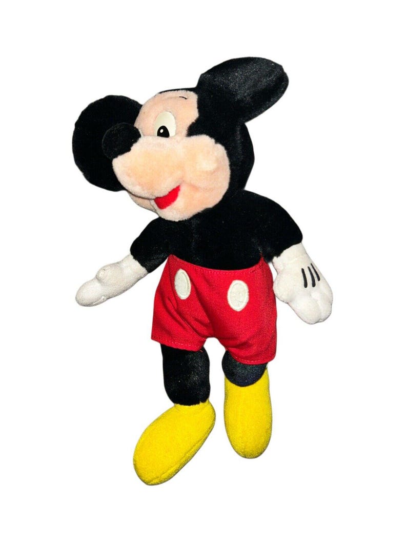 K&ouml;nnte beinhalten: Ein Pl&uuml;sch-Mickey-Mouse-Spielzeug mit schwarzem Fell, roten Shorts mit wei&szlig;en Punkten und gelben Schuhen.