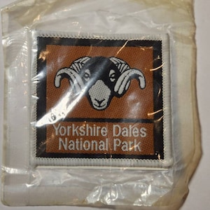 Op de afbeelding: Een bruin en zwart geborduurde patch met een wit schaap en de tekst "Yorkshire Dales National Park".