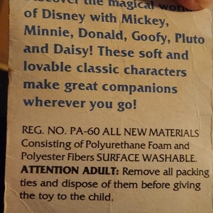 K&ouml;nnte beinhalten: Nahaufnahme eines Produktetiketts mit dem Text "Entdecken Sie die magische Welt von Disney mit Mickey, Minnie, Donald, Goofy, Pluto und Daisy! Diese weichen und liebenswerten klassischen Figuren sind gro&szlig;artige Begleiter, wohin Sie auch gehen! REG. NO. PA-60 ALL NEW MATERIALS Consisting of Polyurethane Foam and Polyester Fibres SURFACE WASHABLE. ATTENTION ADULT: Remove all packing ties and dispose of them before giving the toy to the child."