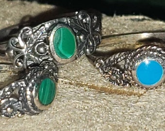 Peut inclure: Trois bagues en argent avec des motifs ornés et des pierres colorées. Les bagues présentent des pierres vertes et bleues.