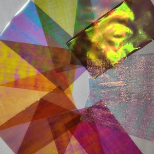 May include: Assortment of iridescent, translucent, rectangular sheets of paper in various colours, including yellow, orange, red, purple, blue, and green. The sheets are arranged in a circular pattern, overlapping each other.