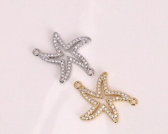 Op de afbeelding: Twee stervormige bedels voor sieraden. Eén is zilverkleurig en de andere goudkleurig. Beide bedels zijn bezet met kleine, heldere kristallen. Elke bedel heeft een kleine lus aan de boven- en onderkant voor bevestiging.