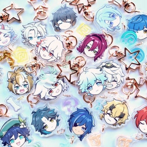 Puede incluir: Una colección de abalorios de personajes de anime coloridos con llaveros en forma de estrella dorada. Los abalorios presentan diferentes personajes con diversas expresiones y peinados.