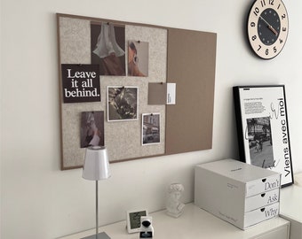 May include: A white desk with a white lamp, a clock, and a white storage box with three drawers. The drawers have the words "Don't Ask Why" printed on them. The desk is against a white wall with a corkboard with photos and the words "Leave it all behind." printed on it. There is a clock on the wall with black numbers and a black and white framed print with text in French.