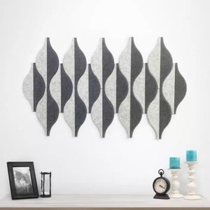 Op de afbeelding: Een set van zes grijze en witte akoestische panelen in een golfpatroon. De panelen zijn in een rij op een witte muur geplaatst. De panelen zijn gemaakt van vilt en zijn ontworpen om geluid te absorberen.