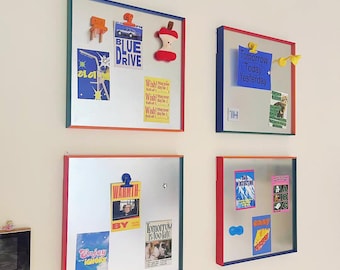 Puede incluir: Cuatro tableros magnéticos cuadrados con marcos rojos, azules y verdes están montados en una pared blanca. Cada tablero contiene varias notas coloridas, pegatinas y pequeños objetos decorativos, incluyendo un peluche con forma de manzana y el texto "BLUE DRIVE".