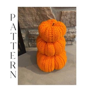 May include: Three crocheted pumpkins stacked on top of each other. The pumpkins are orange and have a textured surface.