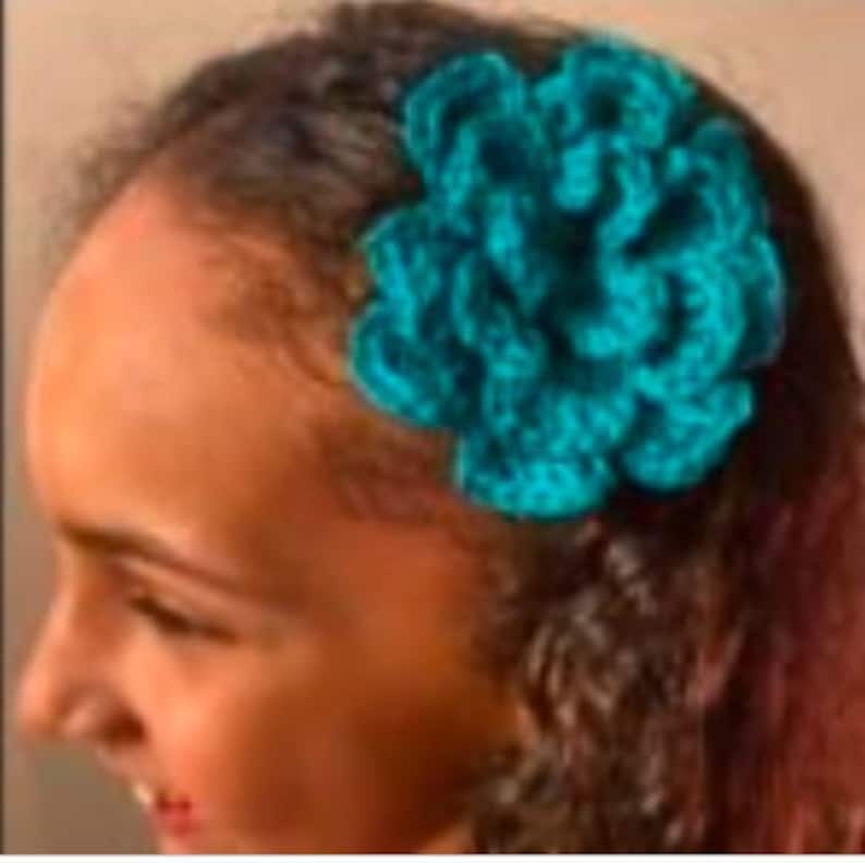 K&ouml;nnte beinhalten: Eine geh&auml;kelte Blumenhaarspange in T&uuml;rkis.