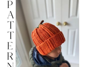 May include: A crocheted pumpkin hat in orange with a green stem. The hat is worn by a child.