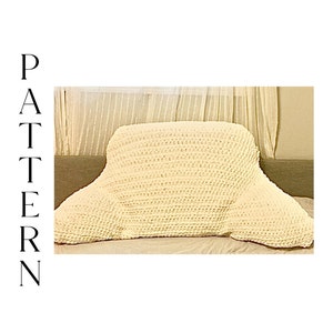 Op de afbeelding: Een wit gehaakt kussen met een unieke vorm, ontworpen voor comfort en ondersteuning. Het is perfect om te loungen op een bank of bed.