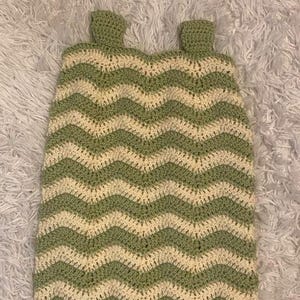 Puede incluir: Una manta de crochet con patrón de chevron verde y blanco con borde de flecos.