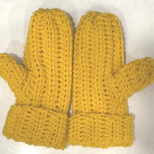 May include: A pair of yellow crochet mittens. The mittens have a ribbed cuff and a textured stitch pattern. These handmade mittens are designed to keep hands warm in cold weather.