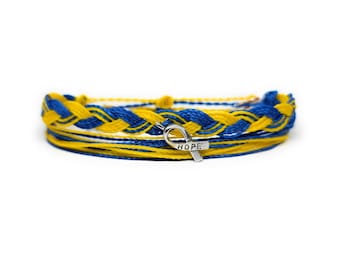 May include: A blue and yellow braided friendship bracelet with a silver ribbon charm that says "HOPE".
