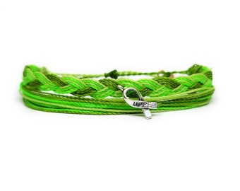 May include: Green and light green braided friendship bracelet with a silver charm in the shape of a ribbon with the word "HOPE" engraved on it.