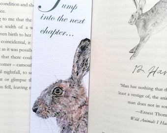 May include: A bookmark featuring a watercolor illustration of a brown hare with the text "Jump into the next chapter..." printed on it. The bookmark is on a book with the text "Raising Hare" and "12. Hare" visible.