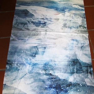 Può includere: Un grande pezzo di tessuto rettangolare con una rappresentazione di paesaggio marino in stile acquerello. L'opera presenta sfumature di blu e bianco, con un focus sulle onde e un cielo nuvoloso. L'effetto complessivo è astratto e atmosferico.