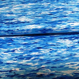 Op de afbeelding: Blauw en wit abstract stof met een waterachtig patroon. De stof is doormidden gevouwen, waardoor het patroon aan beide kanten zichtbaar is.