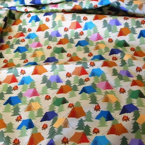 Może przedstawiać: Beżowy materiał z powtarzającym się wzorem kolorowych namiotów i zielonych drzew. Namioty są w różnych kolorach, w tym czerwonym, niebieskim, pomarańczowym, żółtym i fioletowym. Przed każdym namiotem znajdują się małe pomarańczowe płomienie.