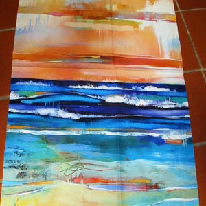 Könnte beinhalten: Abstraktes Gewebe mit einem Strandmotiv. Das Kunstwerk zeigt eine lebendige Farbpalette aus Blau-, Orange- und Gelbtönen, die Meereswellen, einen Sandstrand und einen farbenfrohen Himmel darstellen. Der Stoff ist wahrscheinlich Baumwolle.