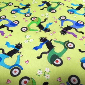 Puede incluir: Tela con un patrón repetido de gatos negros montando scooters azules y verdes, con corazones rosas y flores blancas sobre un fondo verde claro. Los gatos llevan bufandas.