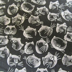 Könnte beinhalten: Schwarz-weißes Stoffmuster mit sich wiederholenden, stilisierten Katzenköpfen.